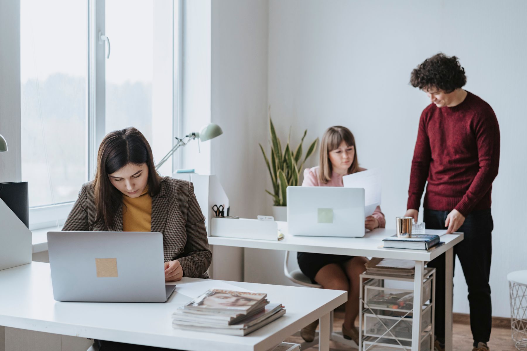 Dua orang bekerja di meja kantor dengan laptop terbuka